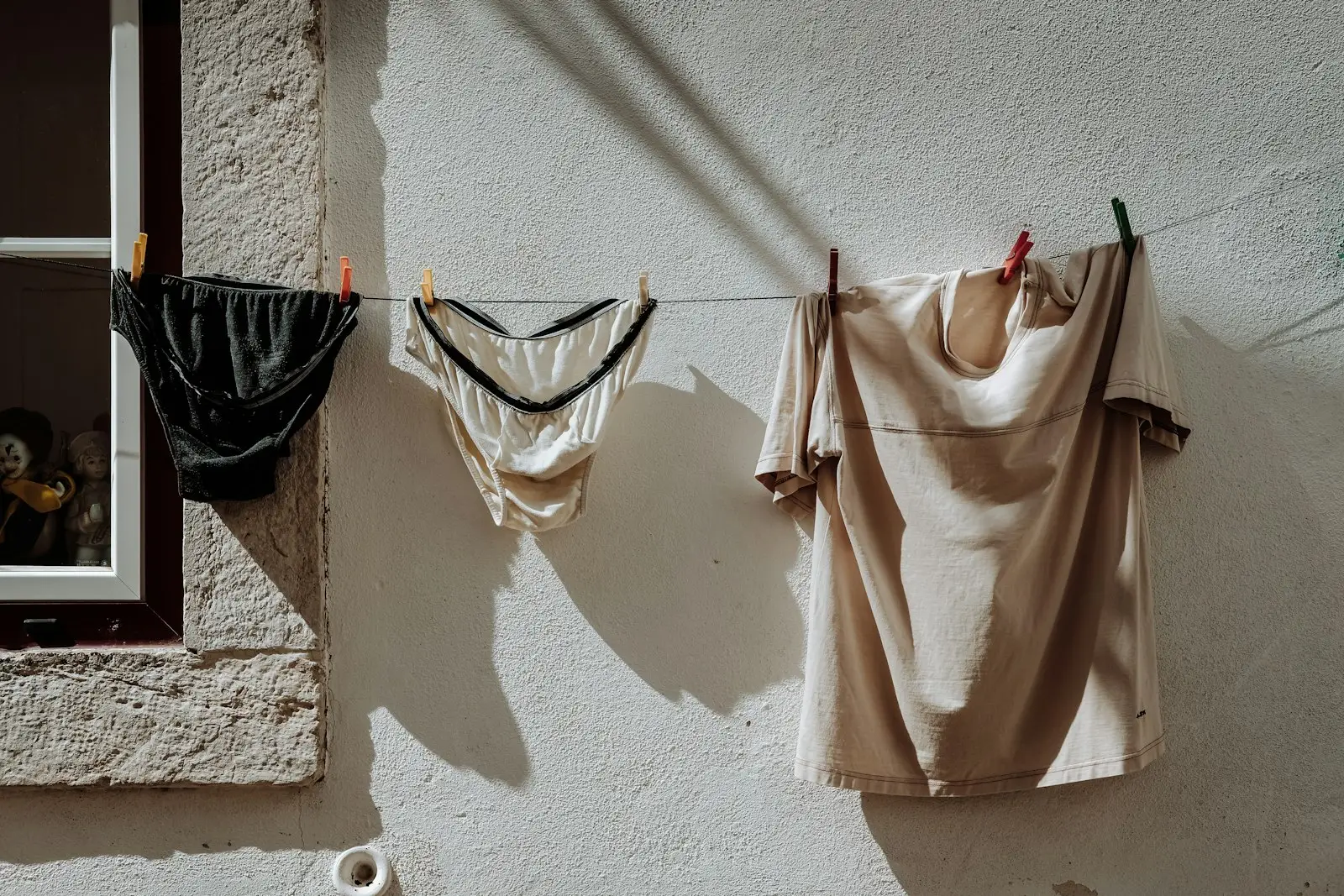 Bras and camisoles drying on a line against a white wall