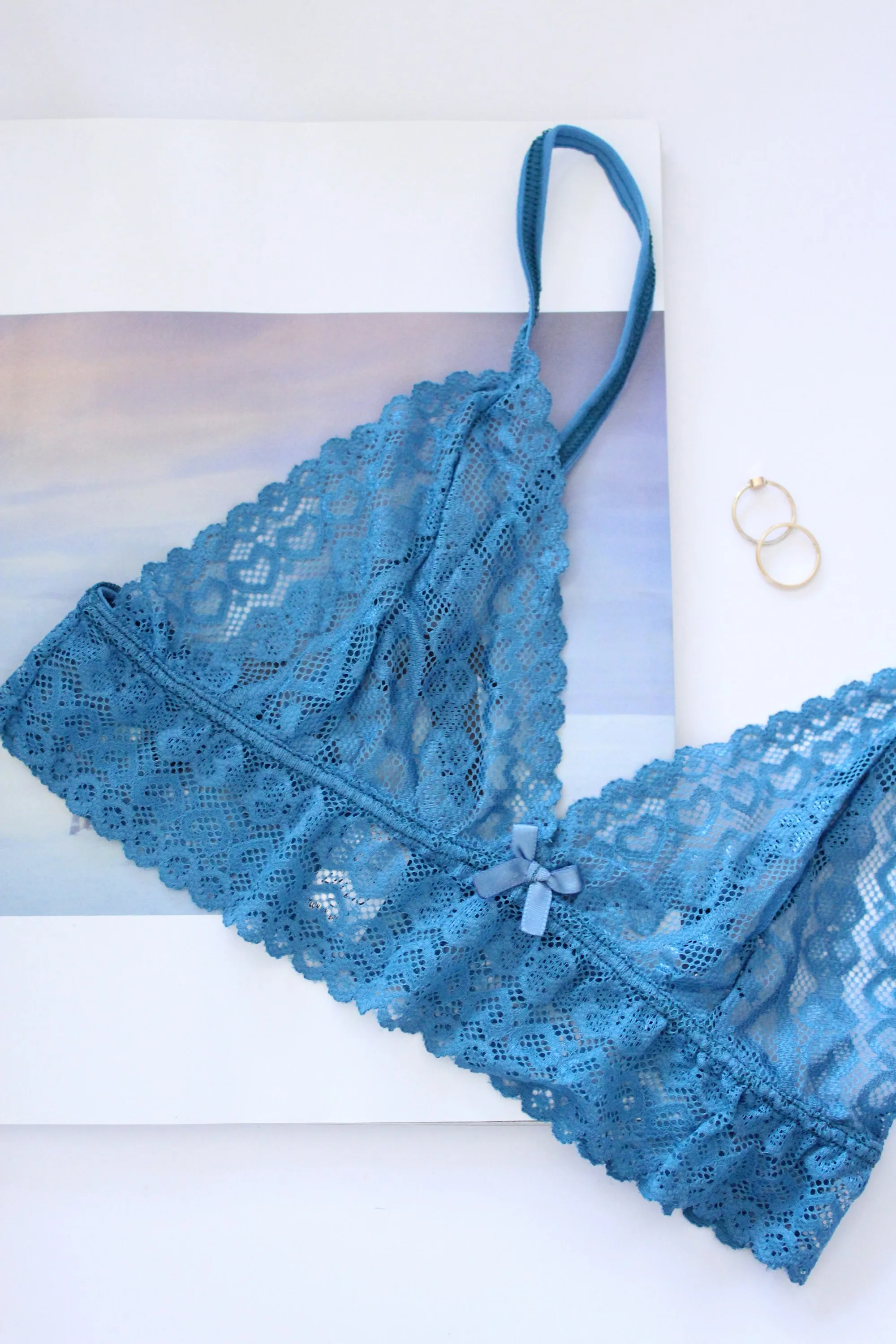 A blue lace wire-free bra with triangle cups on a white surface