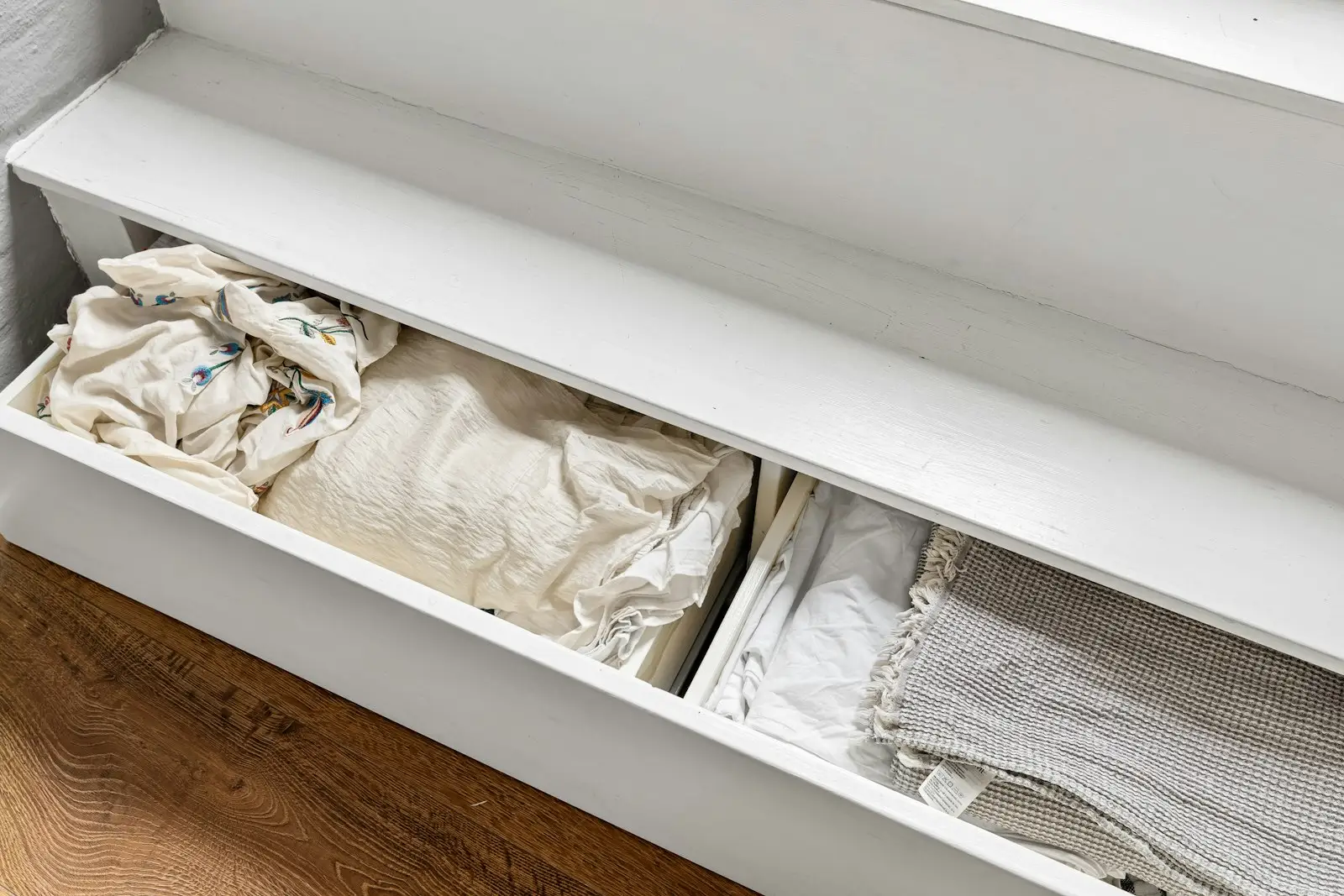 An open white drawer of neatly folded clothes