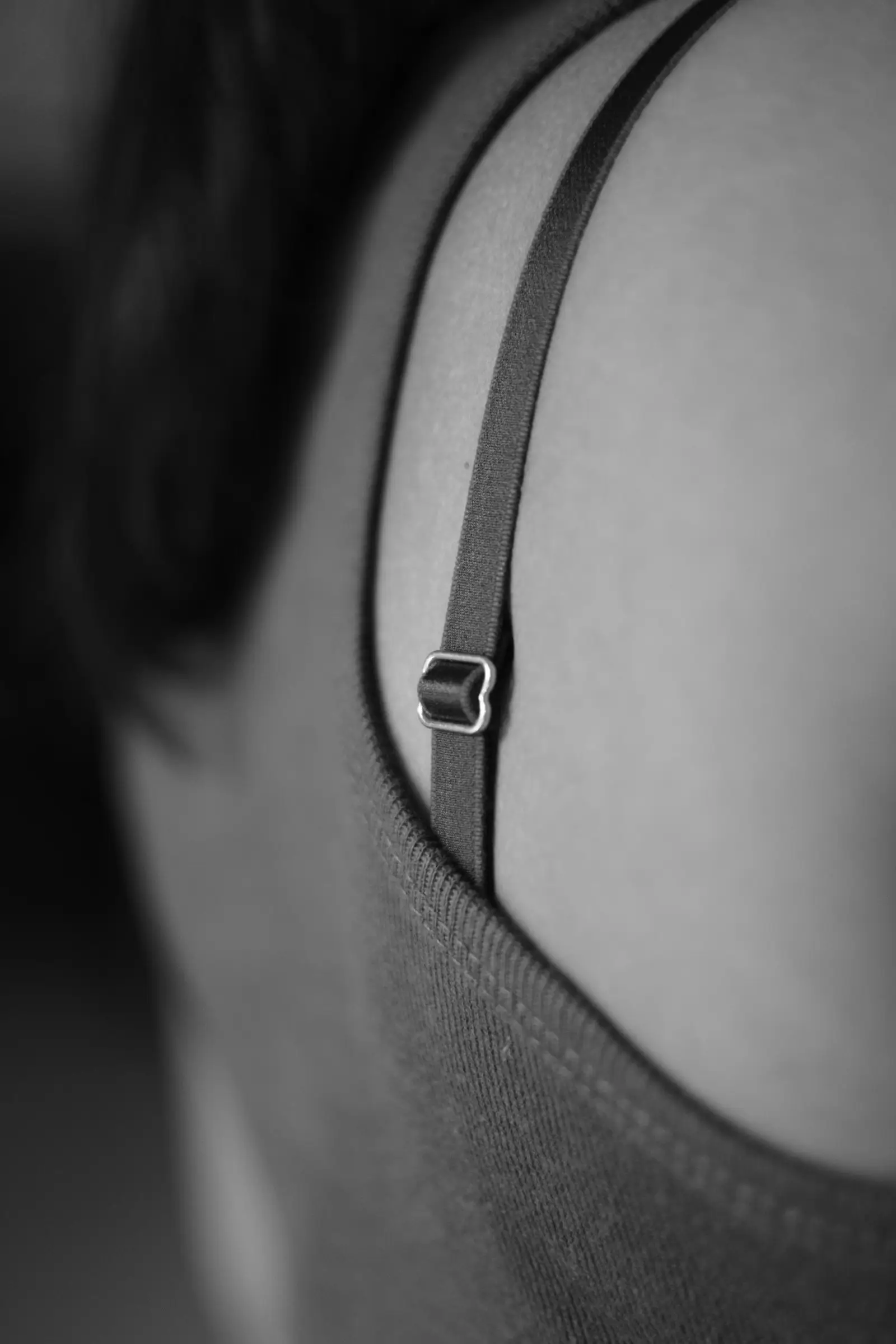 Black and white close-up of a bra strap adjuster on a shoulder