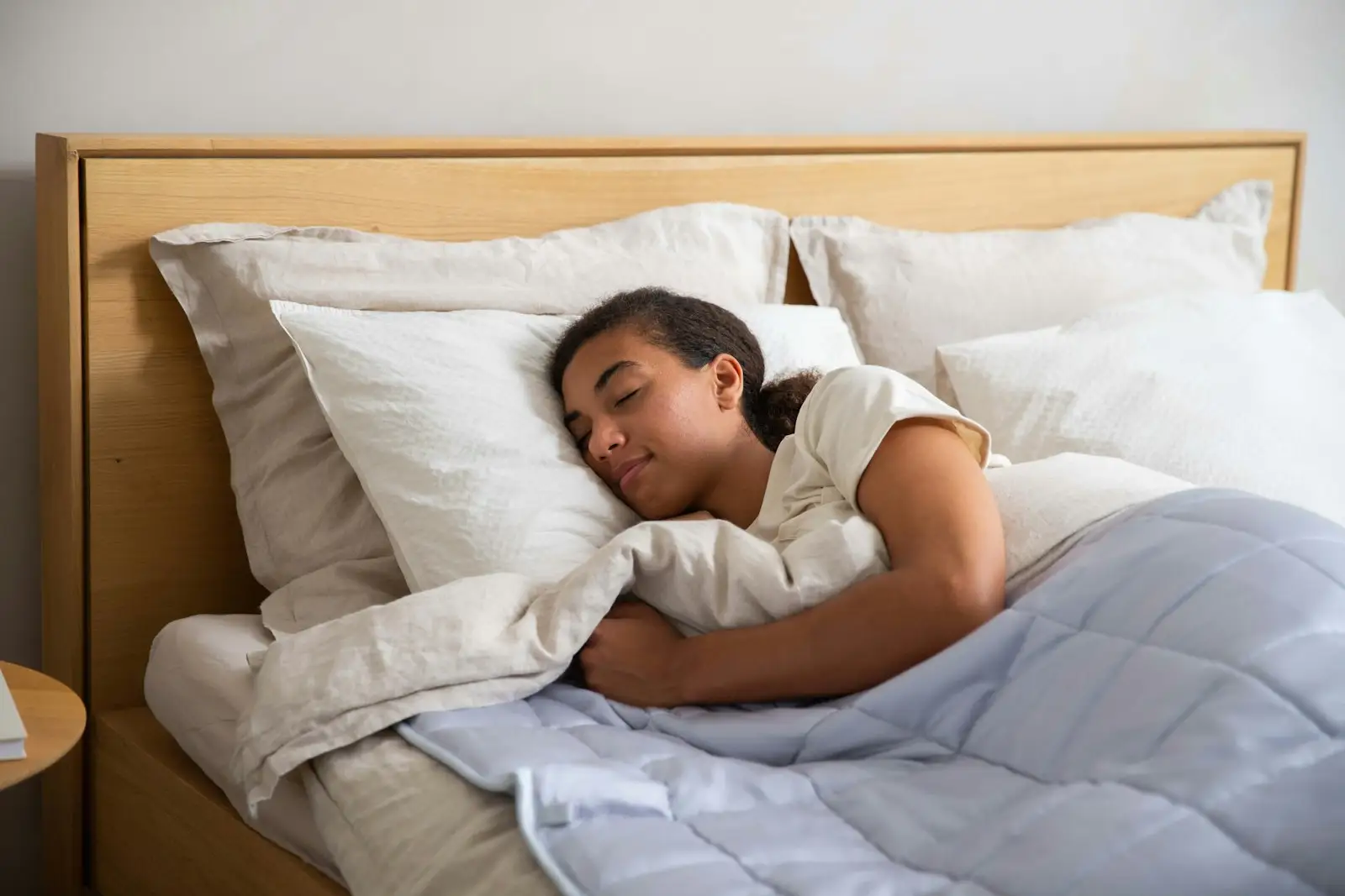 A woman asleep in a T-shirt under a soft blanket