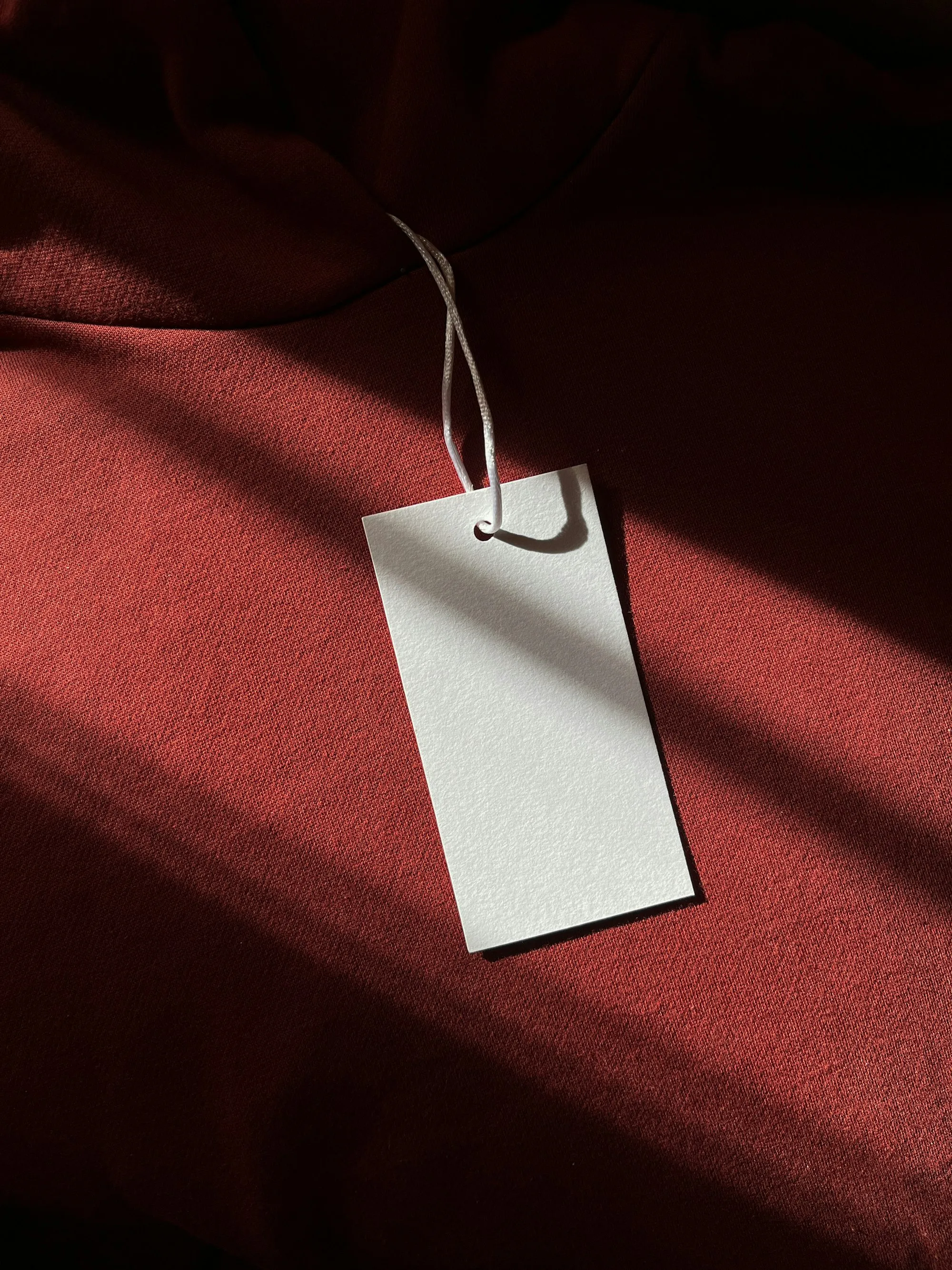 A blank white tag hanging from a red garment