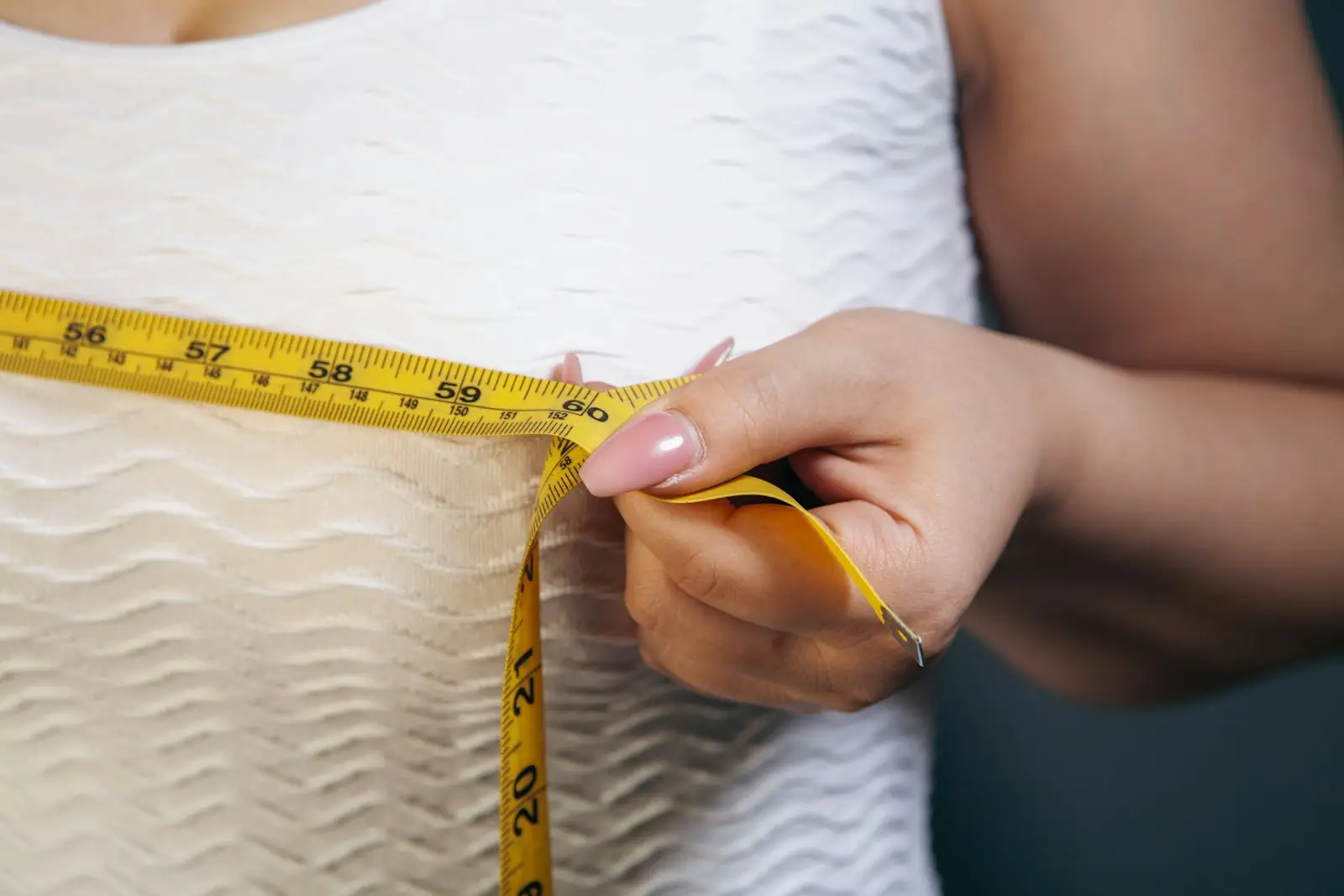 A woman measuring around her ribcage with a yellow tape measure