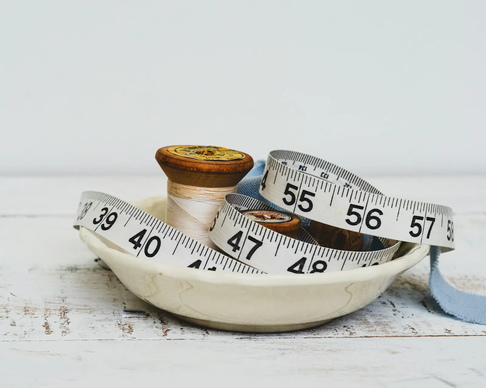 Two soft measuring tapes coiled in a small ceramic dish