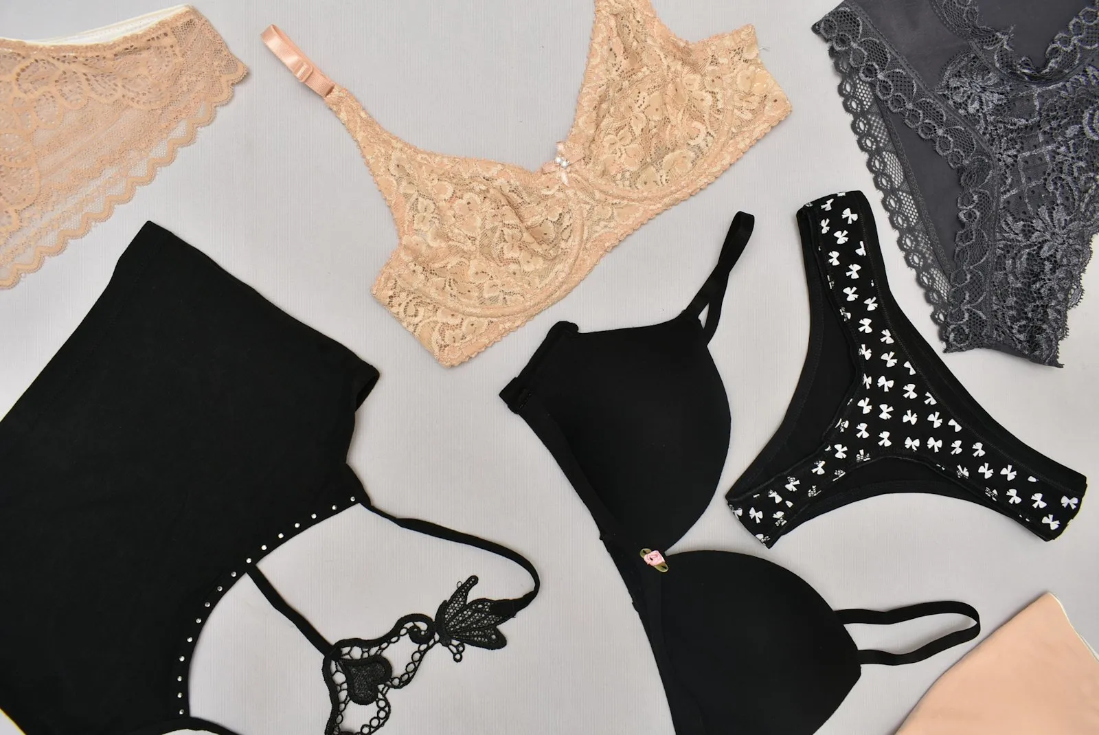 A nude lace bra and a black molded-cup bra laid flat beside matching underwear