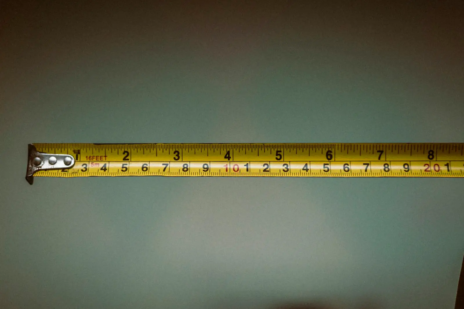 A tape measure extended in front of a soft green background