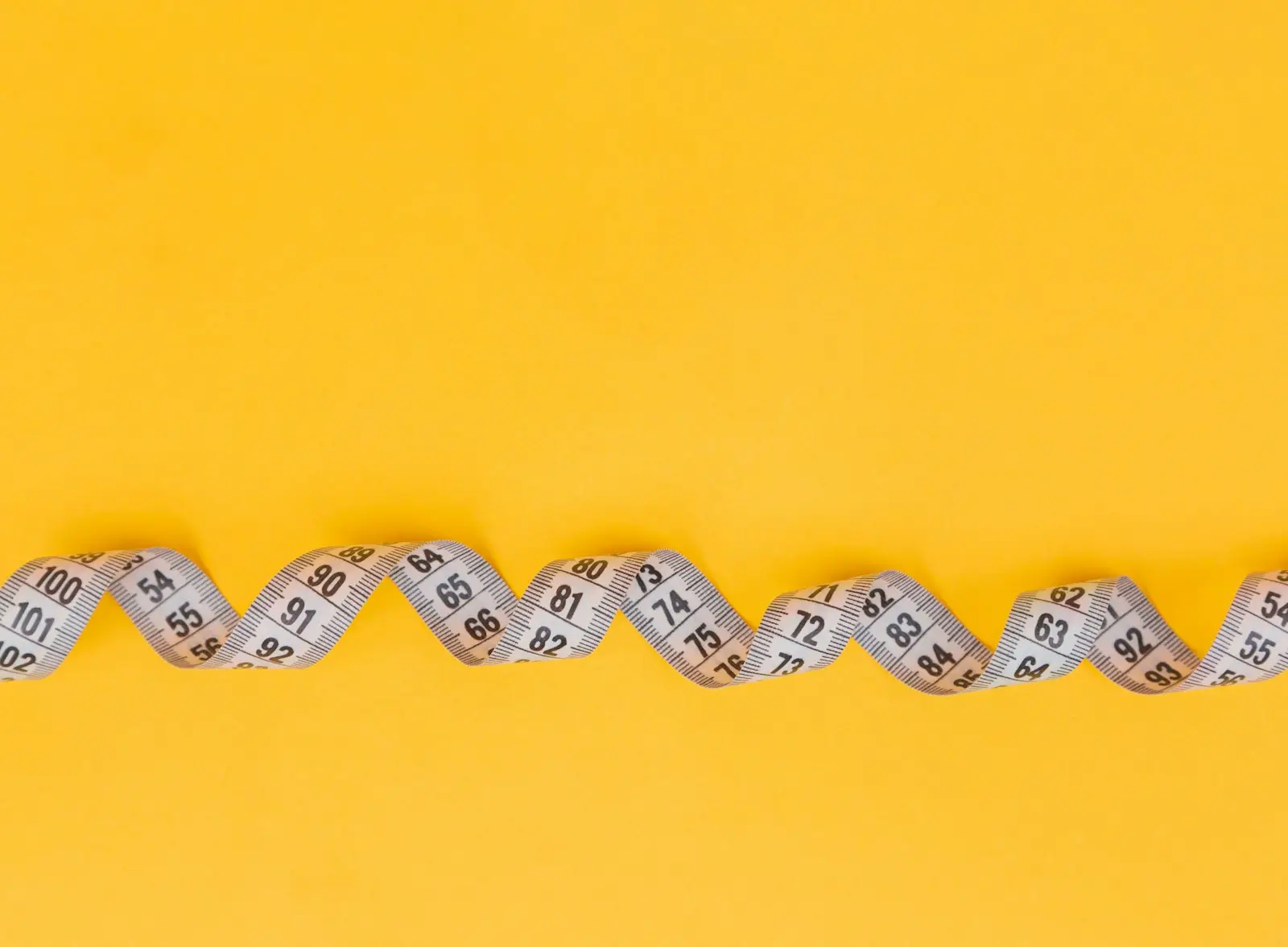 A measuring tape curving across a yellow background
