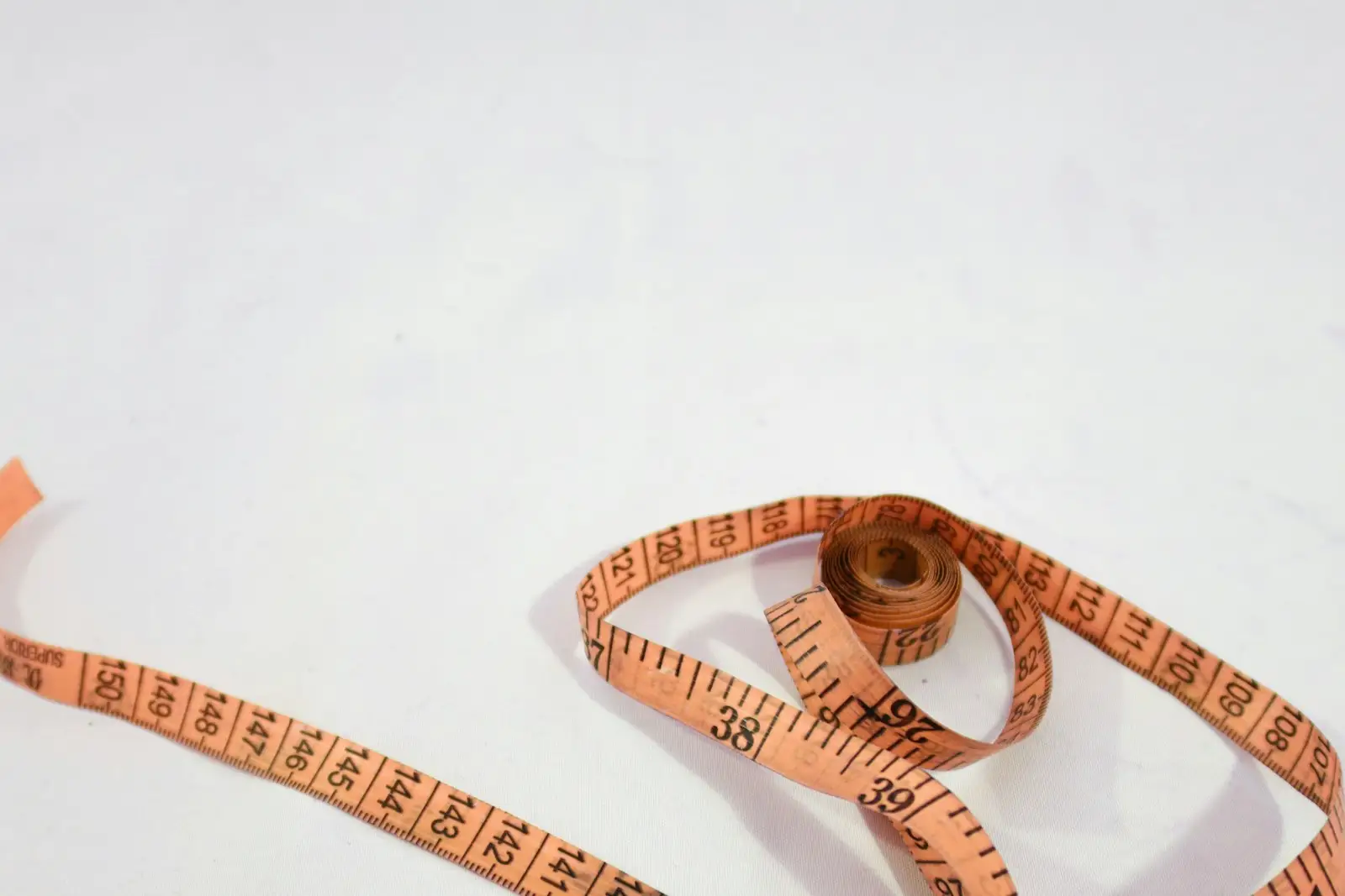 An orange measuring tape unrolled on a white background