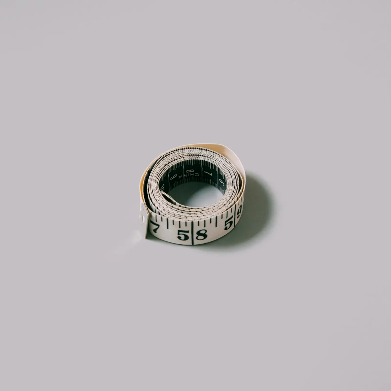 A small rolled-up measuring tape on a grey background
